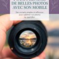 Une femme souriante prenant des photos avec son smartphone dans un parc ensoleillé.